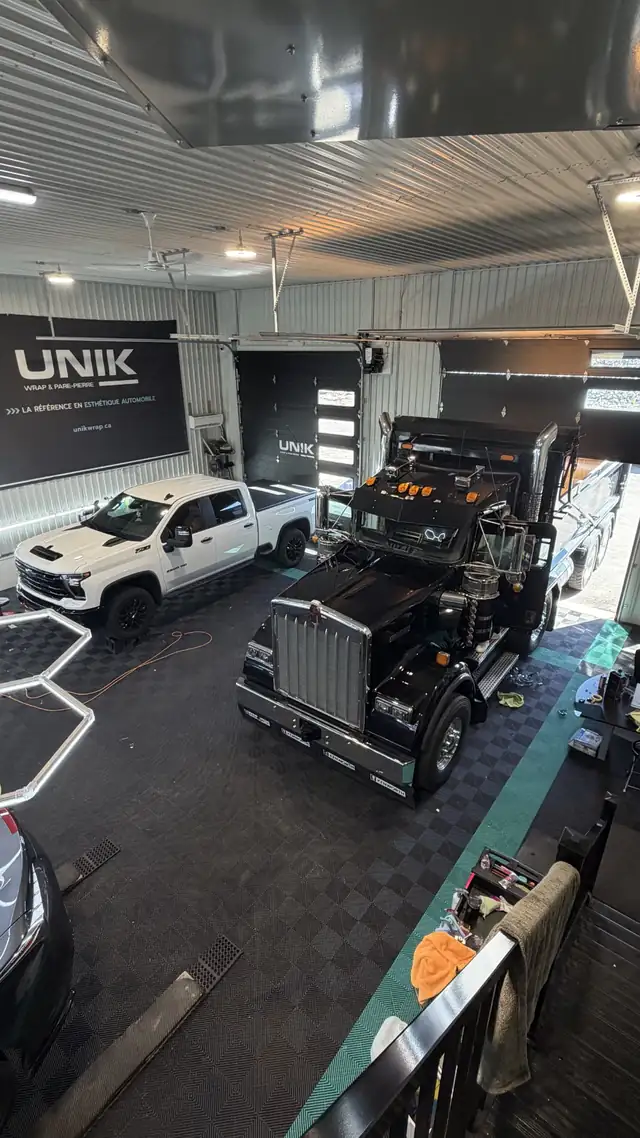 Camion lourd noir et pickup Chevrolet Silverado blanc dans l’atelier UNIK