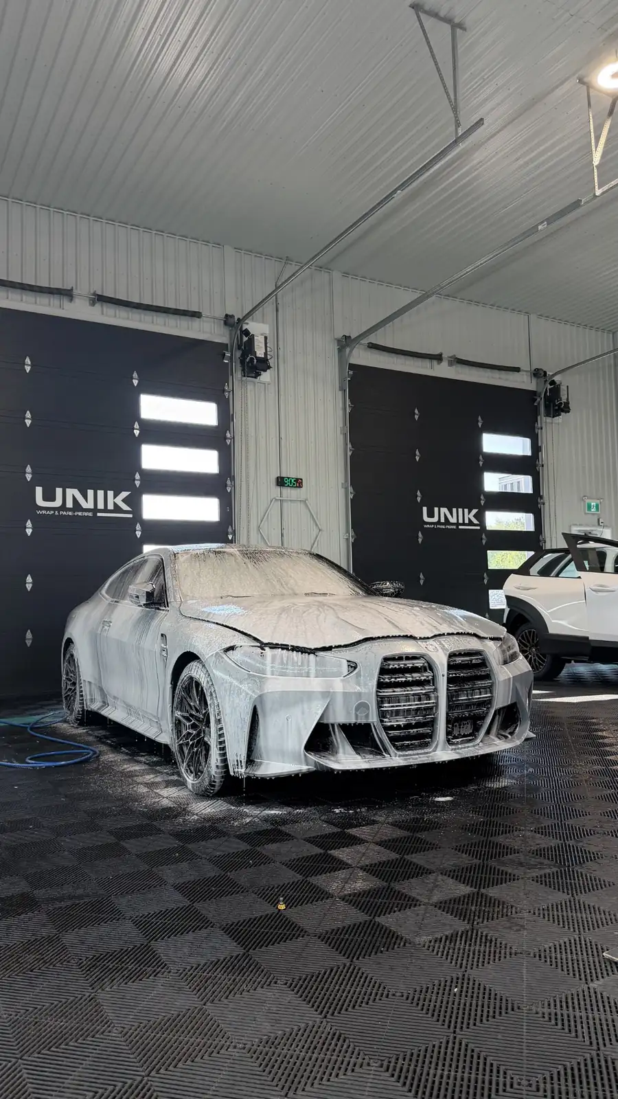BMW M4 couverte de mousse pendant le lavage de préparation dans l’atelier UNIK